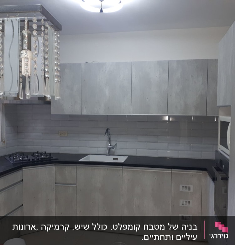 מטבח מודרני עם ארונות אפורים, כיור וכיריים.